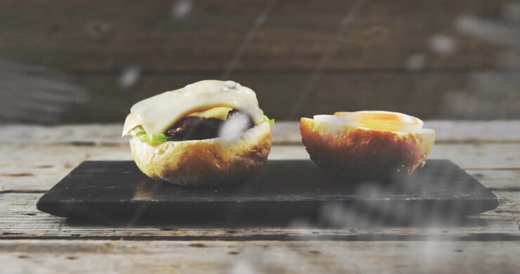 Scrolling world-map overlays covering and revealing two bun halves on wooden table, creating focus