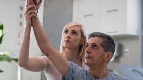 fisioterapeuta femenina estirando el brazo de un hombre mayor.