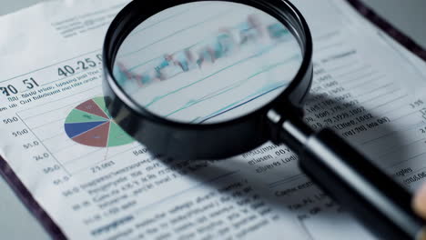 magnifying glass on financial charts and data analysis
