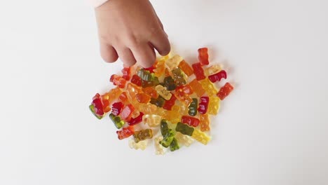 child's hand reaching for a pile of gummy bears