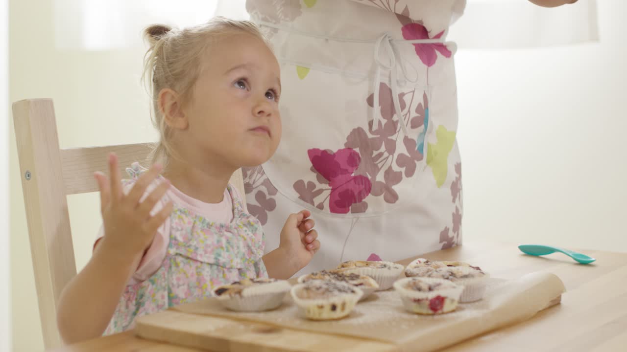 niño interesado en azúcar cayendo sobre muffins horneados