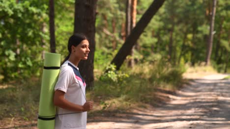 mujer con una alfombra de yoga en el bosque