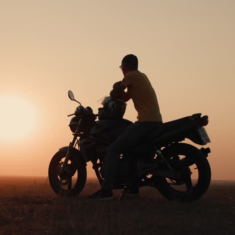 Joven-Sentado-En-Una-Motocicleta-Admirando-La-Puesta-De-Sol