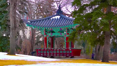 Regierungshaus-Eigentum-Zentriert-Blick-Auf-Den-Koreanischen-Pavillion-Pavillon-An-Einem-Bewölkten-Winternachmittag-Mit-Waldbäumen-Im-Hintergrund,-Während-Eine-Silhouettenperson-Im-Fernen-Hintergrund-Fotografiert