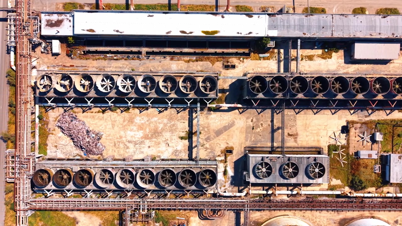 Impianto Industriale con Torri di Raffreddamento. Una vasta area industriale con torri di raffreddamento ed edifici durante il giorno.