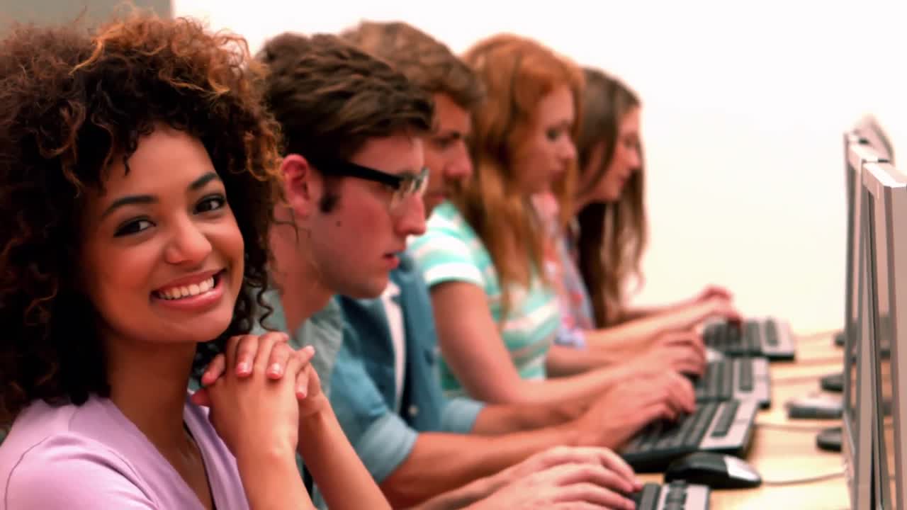 estudiante feliz sonriendo a la cámara en la clase de computadora