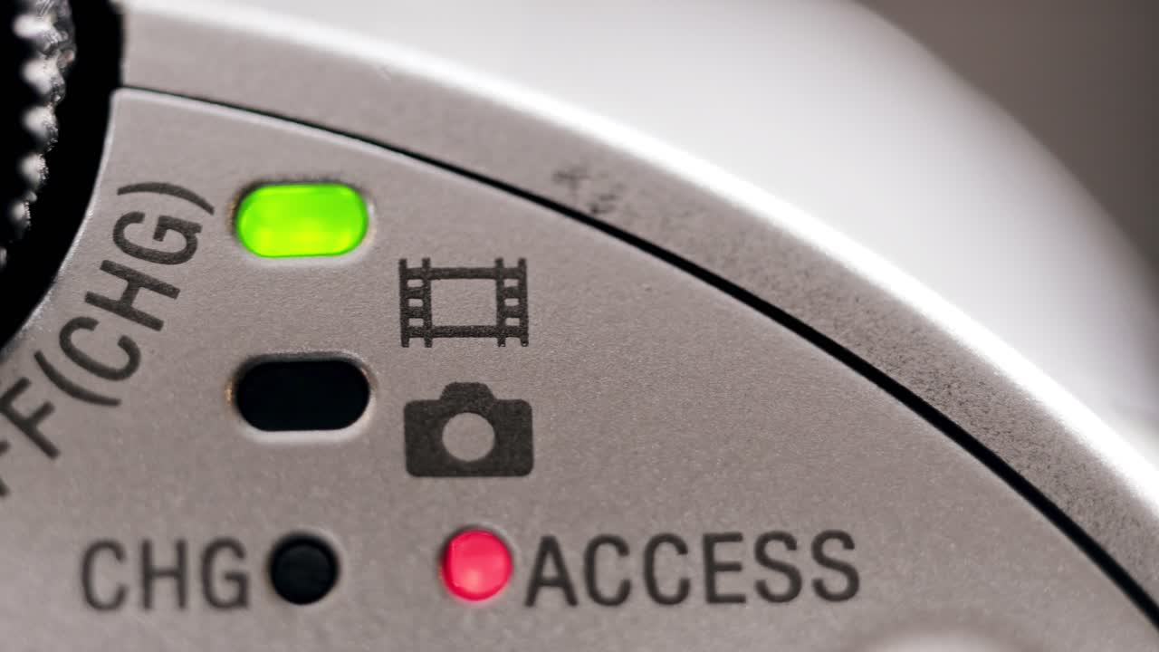 Macro close up of silver camcorder power LED turning on and off with subtle hand movement