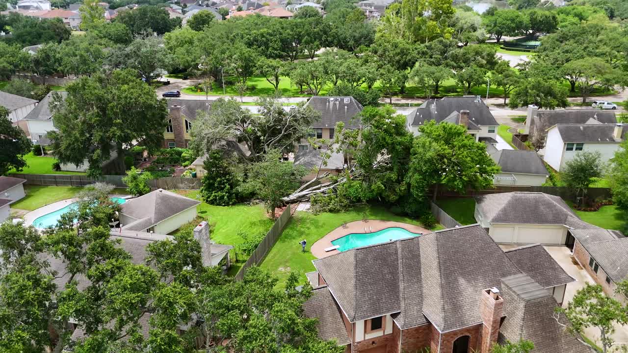 An aerial shot of a fallen tree in the backyard of someone's house.