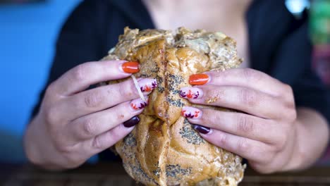 extreme closeup of a classic nyc bodega style chopped cheese sandwich with pickles being opened in half in slow motion by hands with a perfect manicure to reveal the fillings