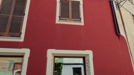 red building with shutters and balcony in barolo