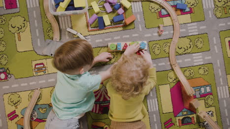 bovenaanzicht van kinderen die spelen met houten stukken liggend op een tapijt in een montessorischoolklas 1