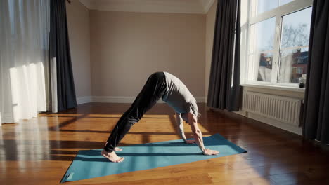 man practicing yoga at home in a sunlit room