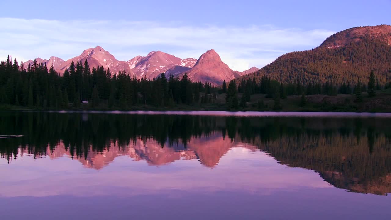 The Rocky Mountains are perfectly reflected in an alpine lake at sunset or dawn 3