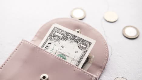 us dollar bill in a pink wallet with coins