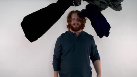 a young red-haired man having laundry falling on his head with an anxious look on his face