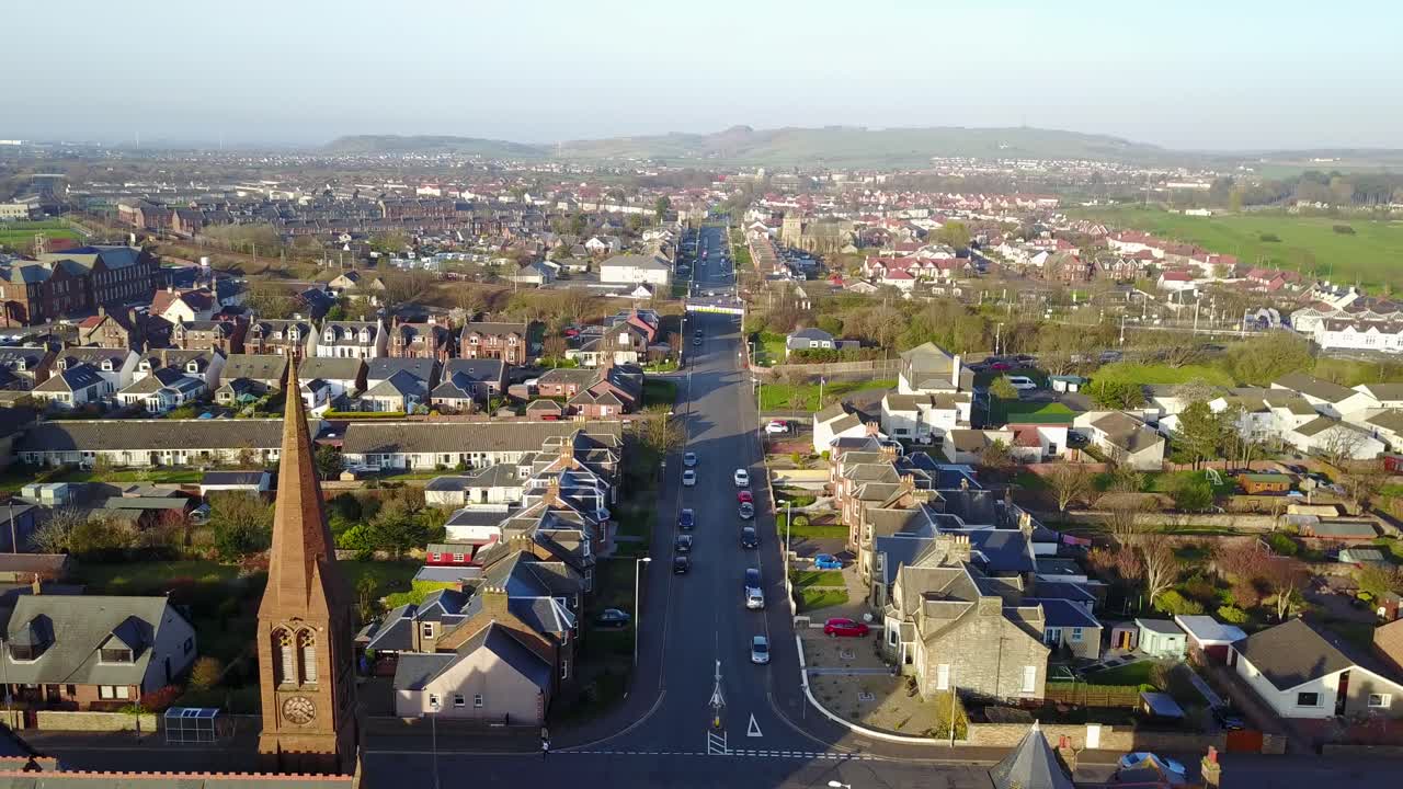 스코틀랜드의 화창한 여름날 큰 집과 거대한 정원이 있는 호화로운 동네에 있는 크고 역사적인 오래된 교구 교회
