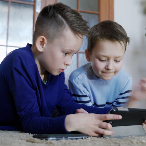 two cute boys playing video game with smartphone indoors, close-up