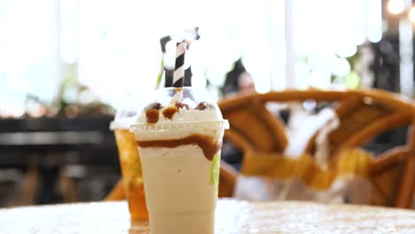 a hand places iced drinks on a sunlit table in a cozy gold coast cafe, capturing a relaxed and inviting atmosphere