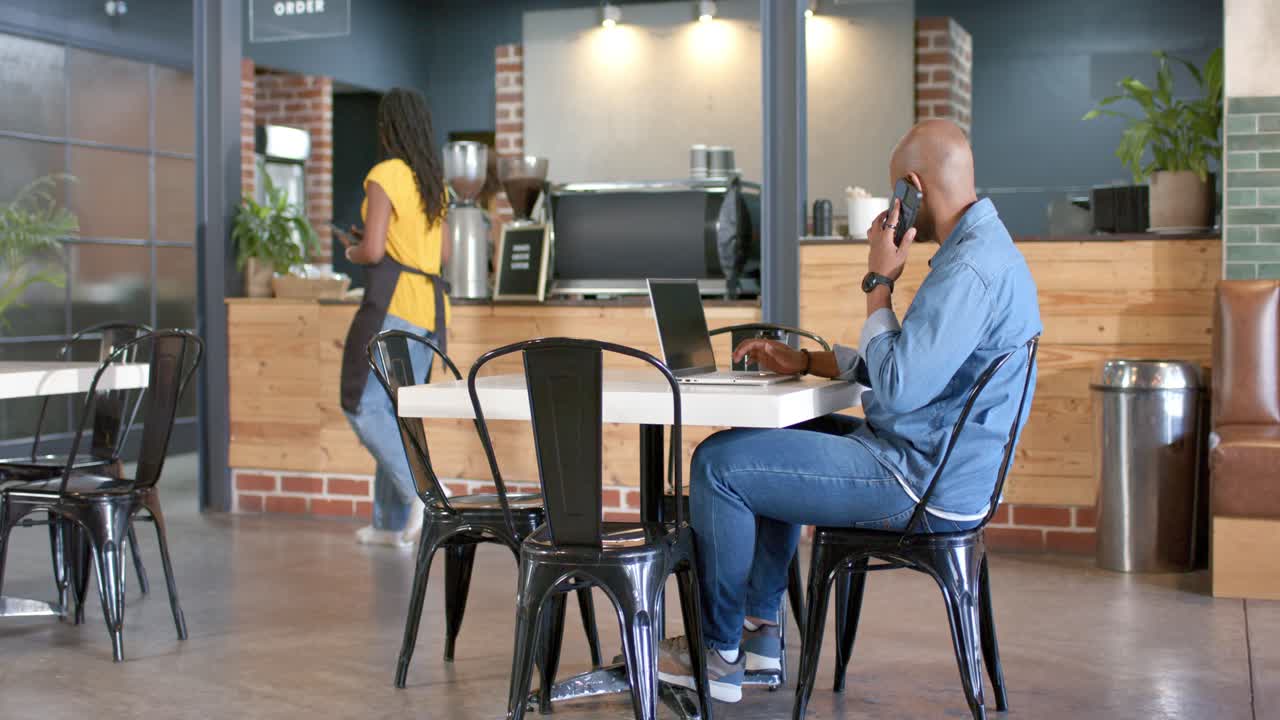 Phone buzzing making African American man pausing typing, answering work call at cafe, copy space