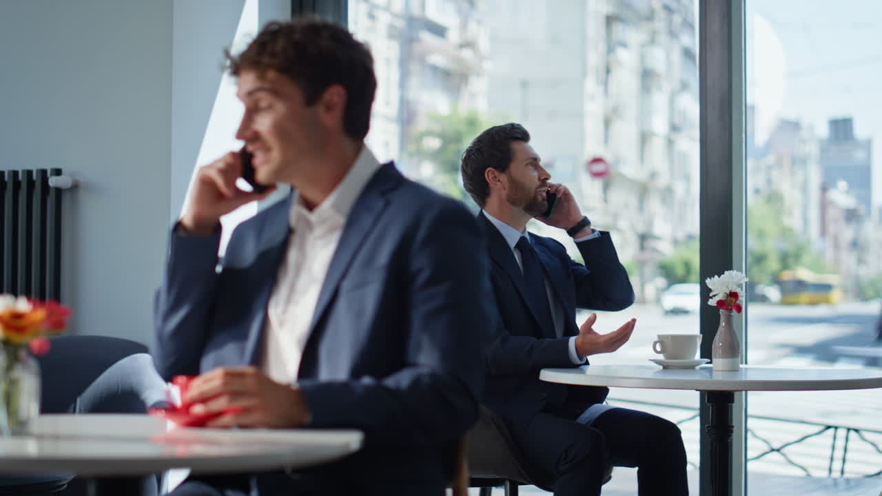 Confident manager calling cafeteria sitting table. Smiling businessman talking