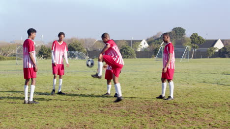 playing soccer, boys in red uniforms practicing on field during school training