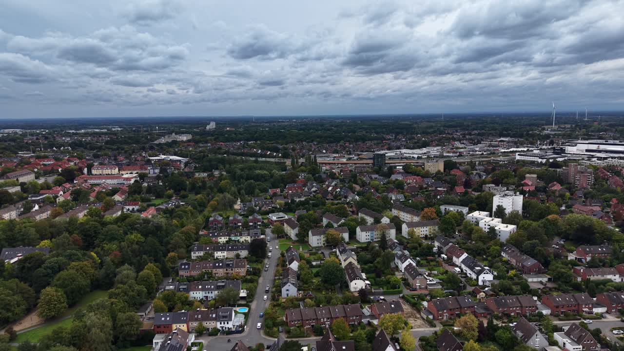 Row of houses and homes between colored trees in fall season. Clouds at sky in October. Descend drone wide shot. German neighborhood and residential area, Europe. Pool in garden