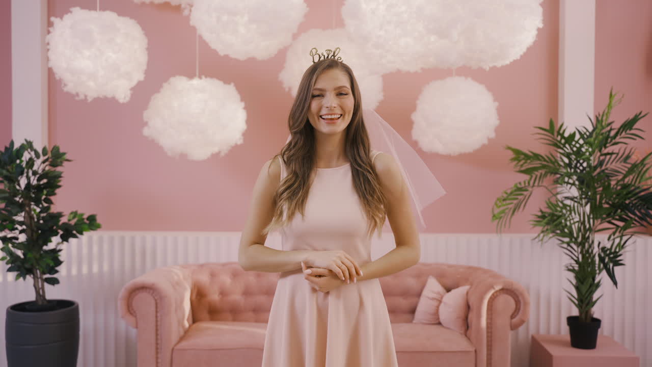 머리 장식과 베일이 카메라에 포즈를 취하는 행복한 총각 소녀의 전면 모습