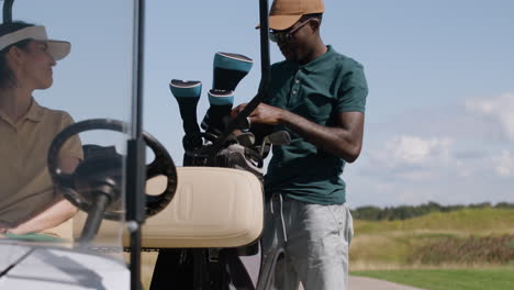 caucasian woman and african american man in a car on the golf course.