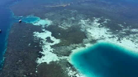 Pulau-Katangan-sandbank-coral-reef-east-of-Komodo-Island-Indonesia-with-diving-tour-ships,-Aerial-pan-left-reveal-shot