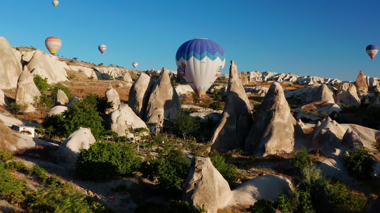 volando a través del paisaje irregular de capadocia hacia un globo aerostático