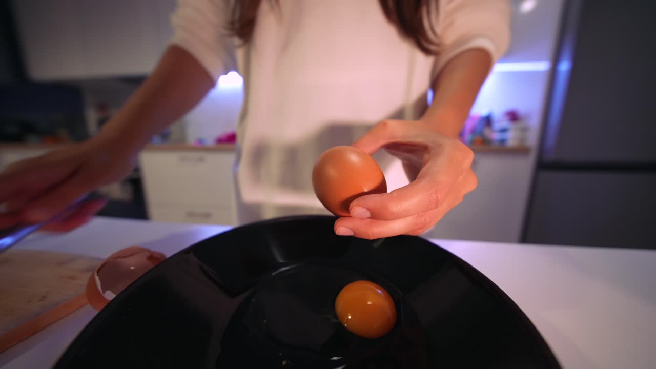 Close-Up of Hands Cracking Fresh Eggs into a Black Plate