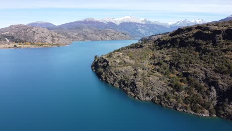 top aerial drone panoramic view beautiful snowy mountains landscape and a cristal clear river along gravel road carretera austral in southern patagonia, chile