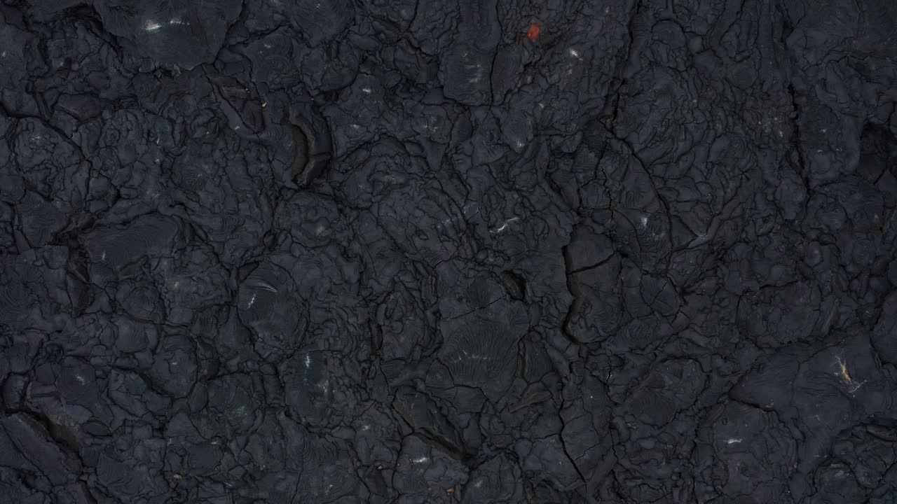 roca basáltica negra oscura campo de lava solidificado superficie rugosa agrietada