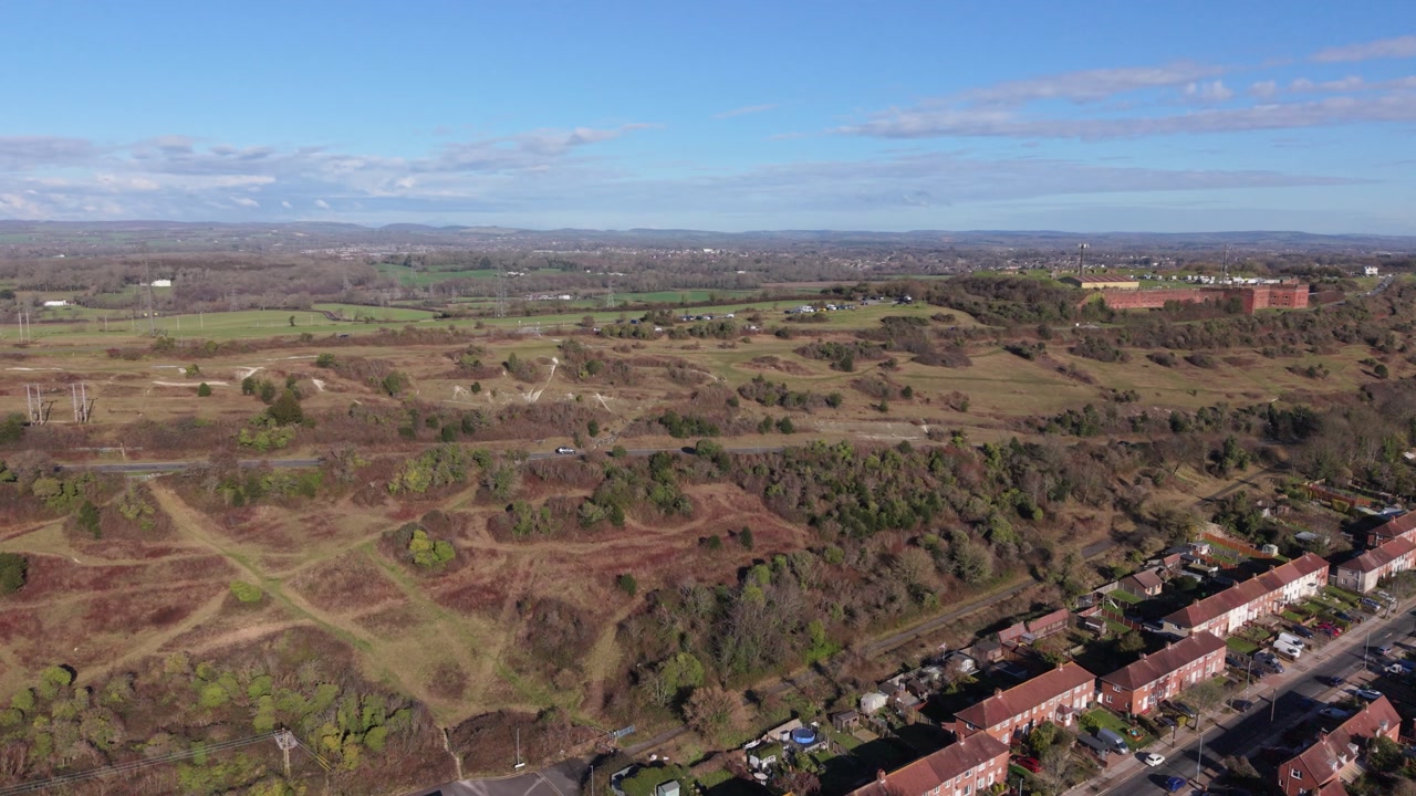 Swanick Hill Portsmouth detailed reveal drone flight over the hill and its scrubland with housing estates at the base of the hill and distant countryside views in bright afternoon sun