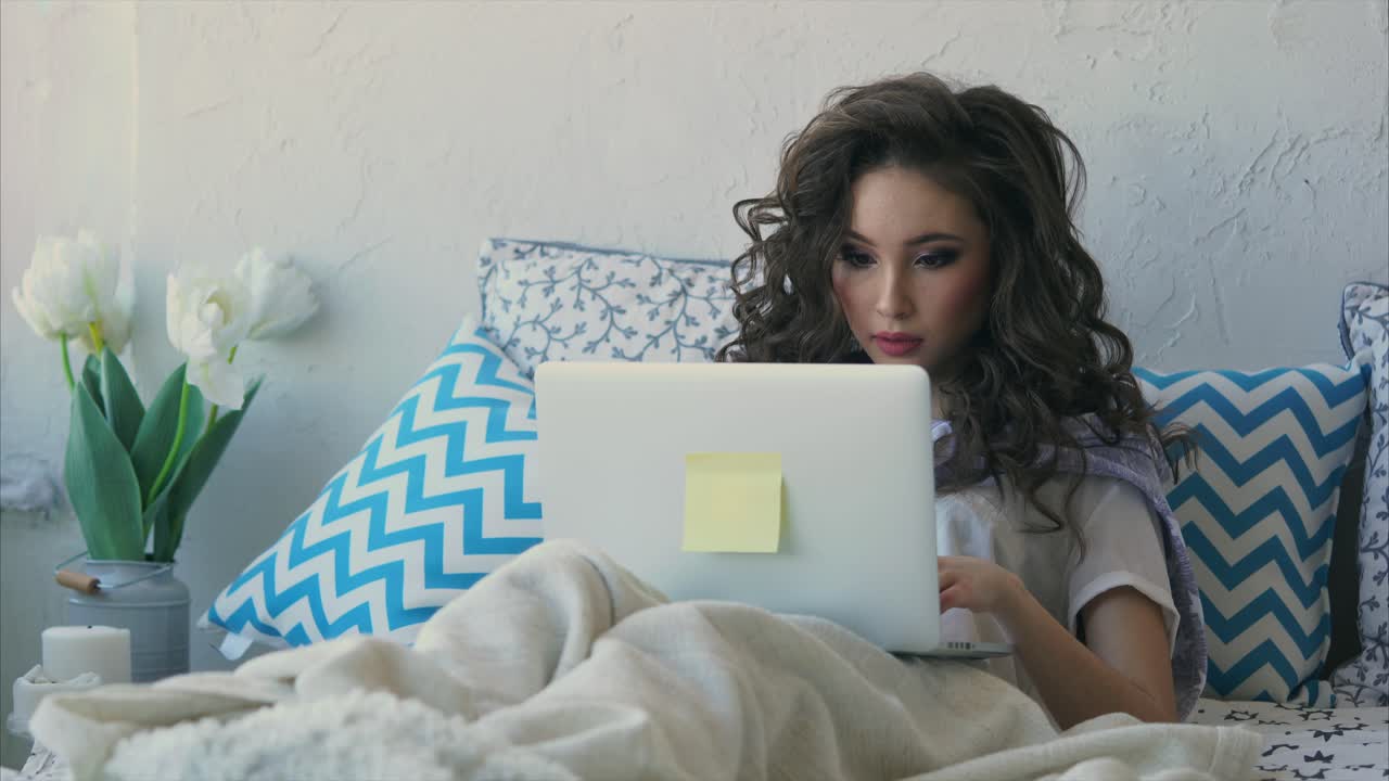 mujer trabajando en una computadora portátil en una cama