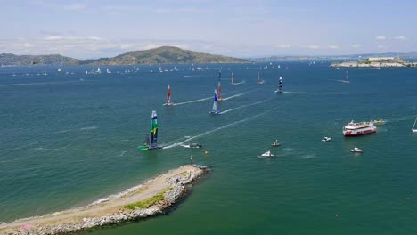 during the sailing grand prix in san francisco 2023, a racing sailboat almost hits a motorboat with press or fans - aerial