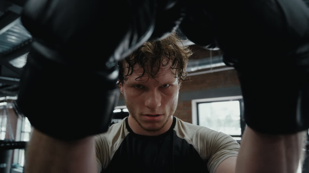 우승 스포츠맨이 링에서 싸움을 끝내고 성공적인  ⁇ 복싱 선수가 체육관에 서 있습니다.