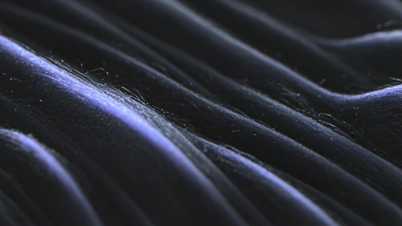 Kameraet bevæger sig og afslører fløjlsfolder i et studie-nærbillede, der viser fibre og blåagtige højdepunkter.