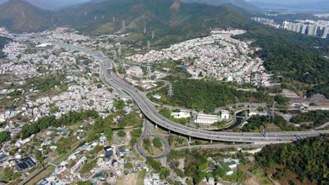 Aerial-view-of-Hong-Kong-outskirts-residential-area,-with-connecting-highway-and-surrounding-mountain-slopes