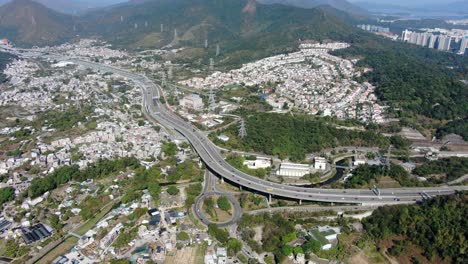 vista aérea de la zona residencial de las afueras de hong kong, con la autopista de conexión y las laderas de las montañas circundantes