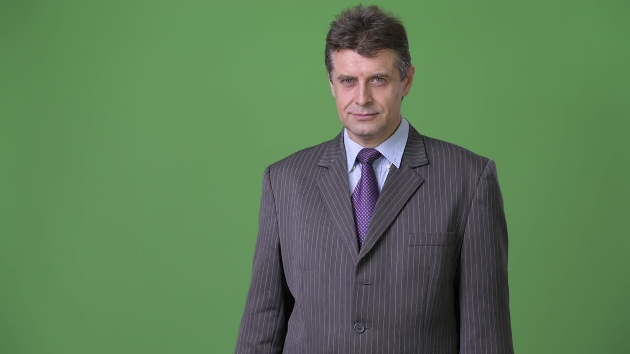 hombre de negocios maduro y guapo contra un fondo verde