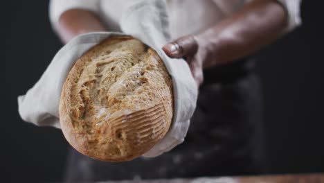 video of cook holding loaf of bread on black background