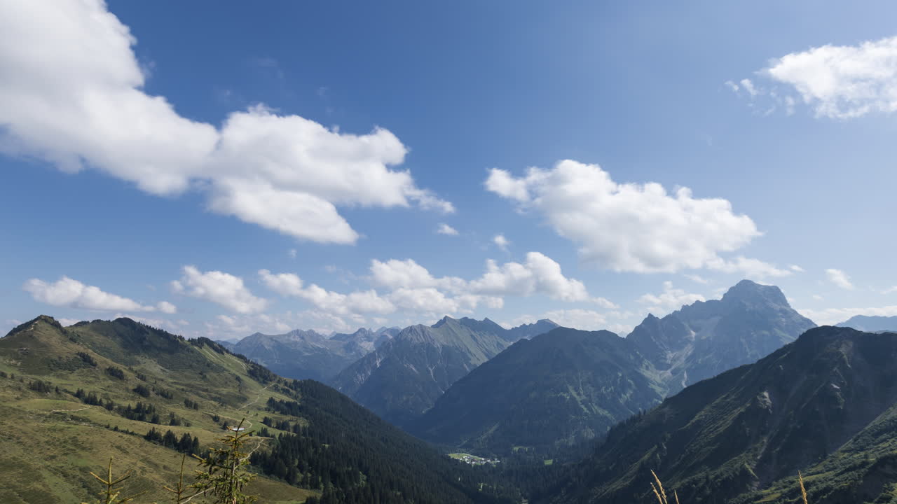 Time-lapse shot of a mountain panorama in the Bregenz Forest with many fleecy clouds passing by with motion blur. Shot on a sunny summer's day