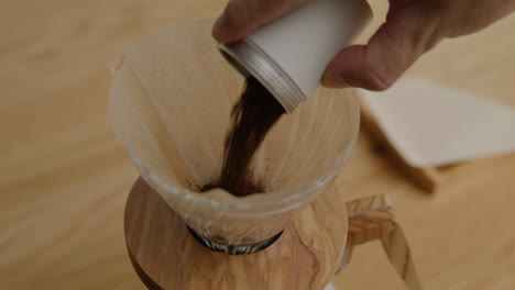 preparing beans to brew coffee in a v60, tight shot with close up on ground beans being poured into the v60 funnel