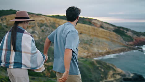 happy couple enjoy walk on ocean coast cloudy day. woman following man to shore.