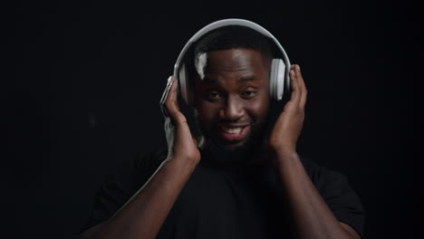 Playful-afro-guy-wearing-headphones-indoors.-Man-listening-music-in-studio