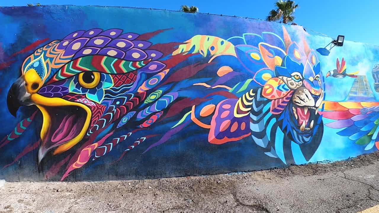 Panoramica verso il basso sull'arte murale colorata in stile Maya che decora le pareti di un edificio a Rocky Point, Messico, Puerto Peñasco, Golfo di California, Oceano Pacifico.