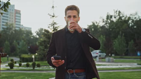 businessman enjoying coffee and using phone in park