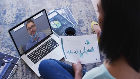 African-american-woman-holding-a-document-having-a-video-call-with-male-colleague-on-laptop