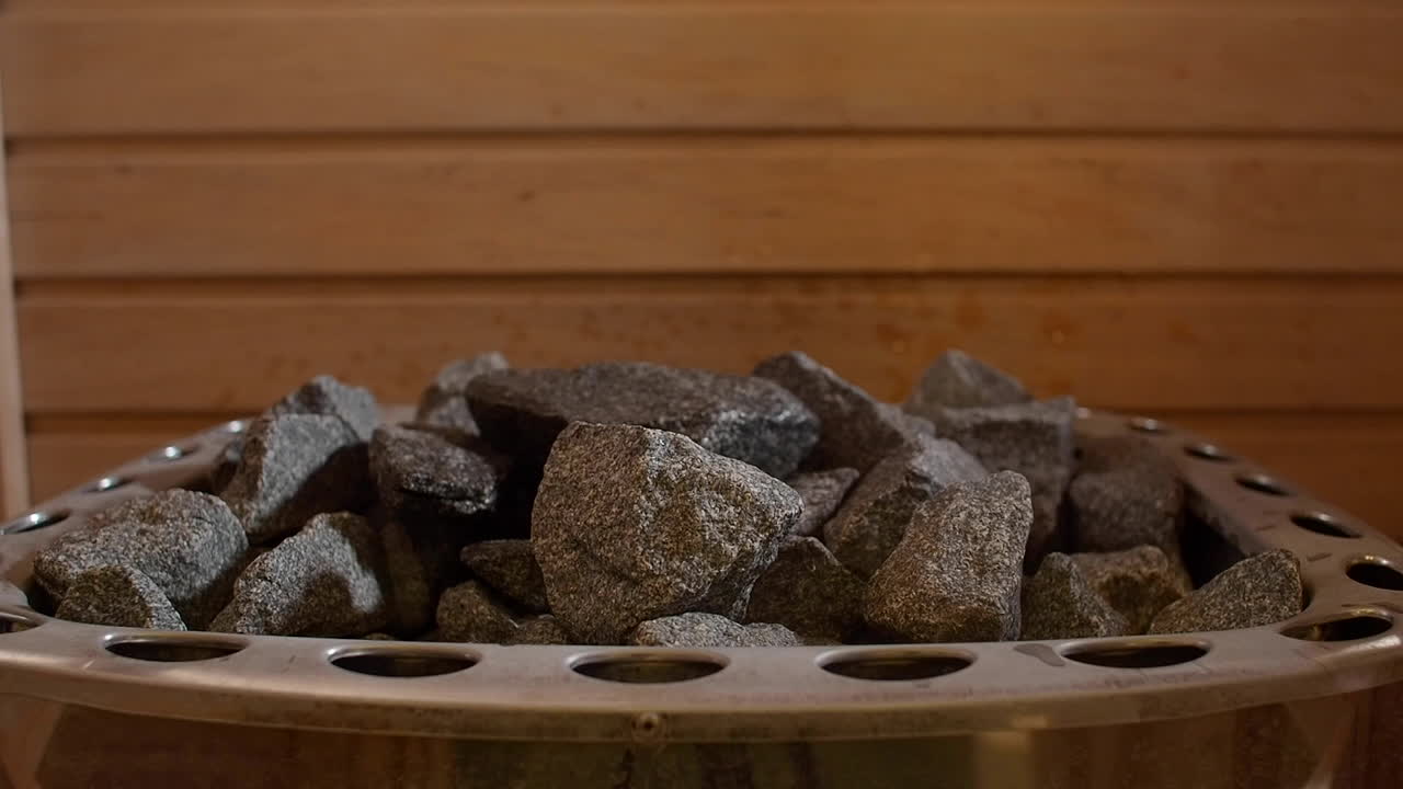 toma de primer plano de las piedras calientes dentro de una sauna de madera, el agua se filtra en las piedras secas